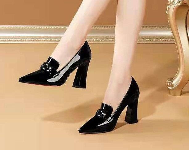 Black patent leather shoes worn by a person on a beige floor.